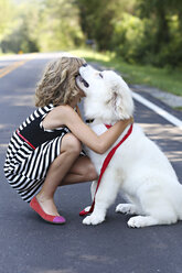 Nahaufnahme eines Mädchens, das einen Hund auf der Straße umarmt - BLEF05608