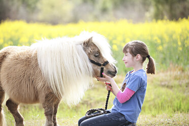 Kaukasisches Mädchen streichelt Pony in ländlichem Feld - BLEF05613