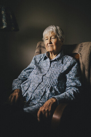 Ältere gemischtrassige Frau sitzt im Sessel, lizenzfreies Stockfoto