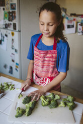 Smiling girl chopping broccoli in kitchen - BLEF05667