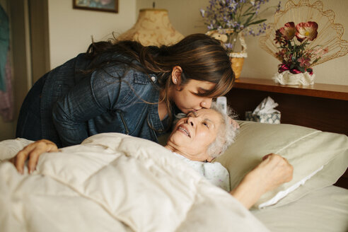 Enkelin küsst die Stirn der Großmutter im Bett - BLEF05678