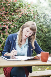 Mixed race businesswoman examining paperwork outdoors - BLEF05686