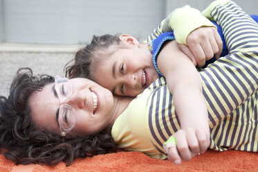 Kaukasische Mutter und Tochter umarmen sich auf dem Teppich - BLEF05698