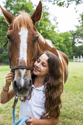 Teenage girl leading horse in field - BLEF05707