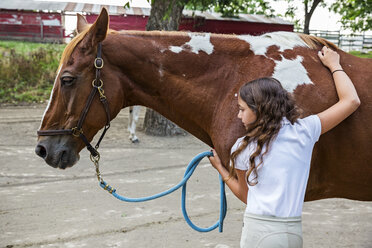 Teenage girl hugging horse on ranch - BLEF05709