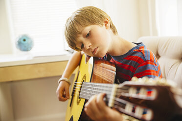 Kaukasischer Junge spielt Gitarre im Wohnzimmer - BLEF05738