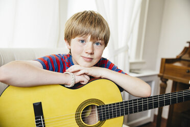 Caucasian boy holding guitar in living room - BLEF05739