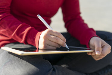 Woman working on digital tablet, using stylus, close-up - FBAF00592