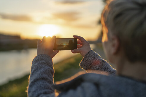 Rückenansicht einer Frau, die den Sonnenuntergang fotografiert, Nahaufnahme - FBAF00628