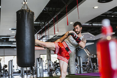 Young man in boxing gloves fighting against punch bag - LJF00023