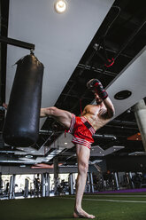 Young man in boxing gloves fighting against punch bag - LJF00024