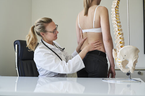 Ärztin untersucht den Rücken eines Patienten in einer Arztpraxis - PNEF01473