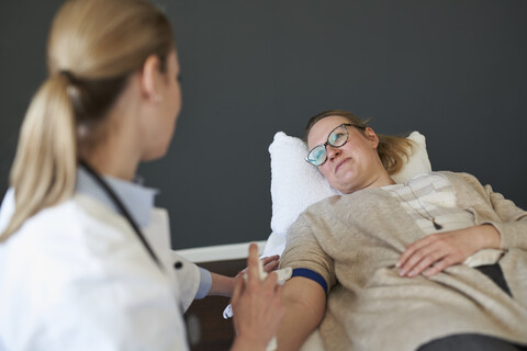 Ärztin bei der Vorbereitung einer Blutentnahme bei einem Patienten in einer Arztpraxis, lizenzfreies Stockfoto