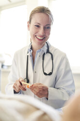 Lächelnde Ärztin bei der Vorbereitung einer Blutentnahme bei einem Patienten in einer Arztpraxis - PNEF01495