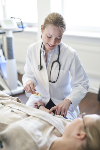 Ärztin bei der Entnahme einer Blutprobe von einem Patienten in einer Arztpraxis, lizenzfreies Stockfoto