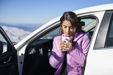 Woman sitting in car having a hot coffee before skiing - JSMF01094