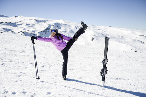 Frau in Skikleidung beim Dehnen vor dem Skifahren in der Sierra Nevada, Andalusien, Spanien - JSMF01097