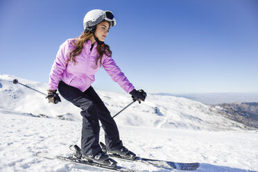 Frau beim Skifahren unter blauem Himmel, Sierra Nevada, Andalusien, Spanien - JSMF01120