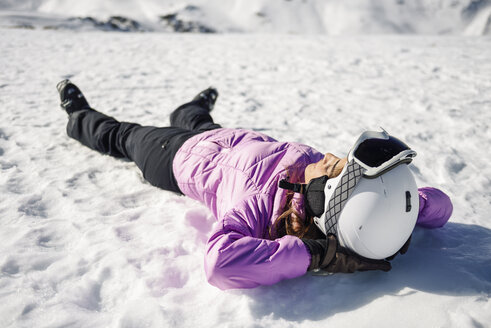 Frau, die nach dem Skifahren auf dem verschneiten Boden liegend eine Pause einlegt, in der Sierra Nevada, Andalusien, Spanien - JSMF01137