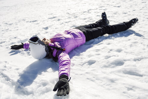 Frau, die nach dem Skifahren auf dem verschneiten Boden liegend eine Pause einlegt, in der Sierra Nevada, Andalusien, Spanien - JSMF01138