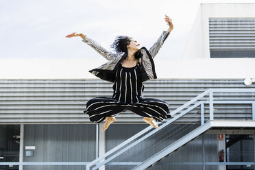 Balletttänzerin, die mit einem Smartphone springt und ein Selfie vor einem Bürogebäude macht - ERRF01420