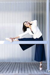 Female ballet dancer during training on a railing, using smartphone - ERRF01444