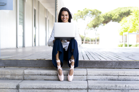 Balletttänzerin mit Laptop auf den Stufen sitzend, lizenzfreies Stockfoto