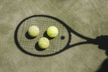 Schatten eines Tennisspielers mit Bällen und Schläger auf dem Platz - LJF00041