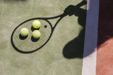 Schatten eines Tennisspielers mit Bällen und Schläger auf dem Platz - LJF00042