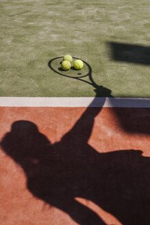 Schatten eines Tennisspielers mit Bällen und Schläger auf dem Platz - LJF00043