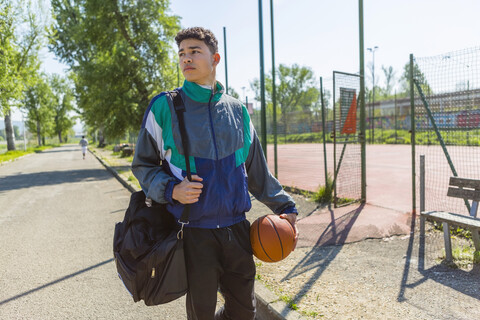 Junger Mann mit Basketball auf dem Basketballplatz, lizenzfreies Stockfoto