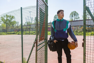 Junger Mann mit Basketball auf dem Basketballplatz - MGIF00481