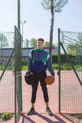 Junger Mann mit Basketball auf dem Basketballplatz - MGIF00483