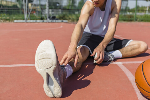 Junger Basketballspieler streckt sein Bein, lizenzfreies Stockfoto