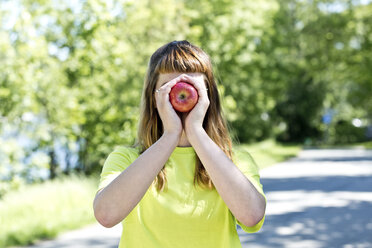 Porträt einer jungen Frau mit Brille, die einen Apfel hält - FLLF00219