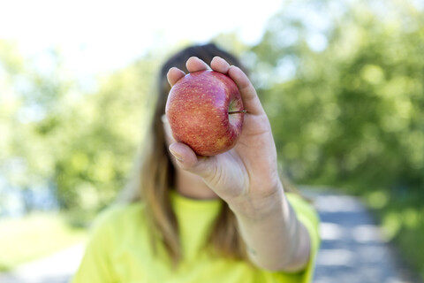 Porträt einer jungen Frau mit Brille, die einen Apfel hält, lizenzfreies Stockfoto