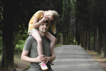 Father carrying daughter on a treelined road - EYAF00248