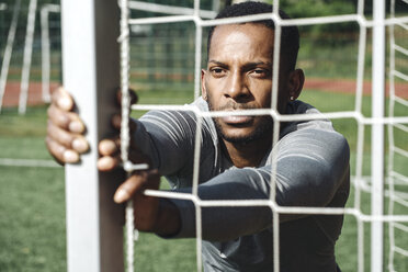 Portrait of sportsman stretching exercise behind net - AHSF00403