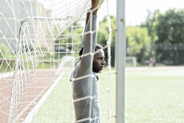 Sportler auf dem Fußballplatz am Torpfosten stehend - AHSF00404