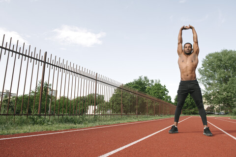 Sportsman stretching his arms on racetrack stock photo
