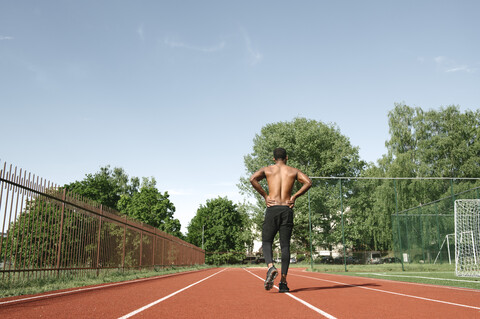 Athletischer Mann, der auf einer Gummirennbahn läuft, Rückansicht, lizenzfreies Stockfoto