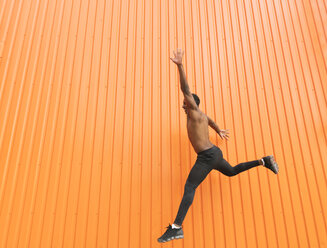 Athlete jumping in front of an orange wall - AHSF00438