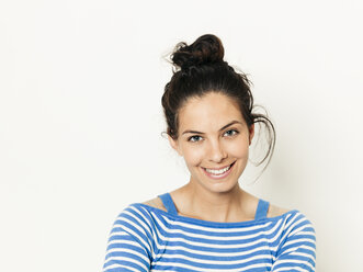 Beautiful young woman with black hair and blue white striped sweater is posing in front of white background - HMEF00420