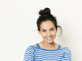 Schöne junge Frau mit schwarzen Haaren und blau-weiß gestreiften Pullover ist vor dem weißen Hintergrund posiert - HMEF00420