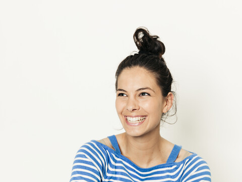 Schöne junge Frau mit schwarzen Haaren und blau-weiß gestreiften Pullover ist vor dem weißen Hintergrund posiert, lizenzfreies Stockfoto