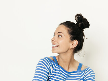 Schöne junge Frau mit schwarzen Haaren und blau-weiß gestreiften Pullover ist vor dem weißen Hintergrund posiert - HMEF00422
