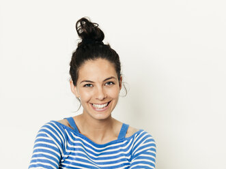 Schöne junge Frau mit schwarzen Haaren und blau-weiß gestreiften Pullover ist vor dem weißen Hintergrund posiert - HMEF00423