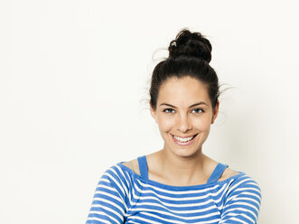 Beautiful young woman with black hair and blue white striped sweater is posing in front of white background - HMEF00424