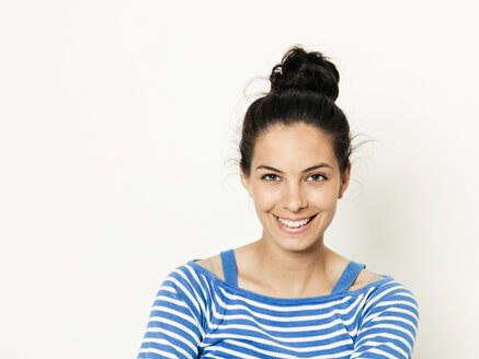 Schöne junge Frau mit schwarzen Haaren und blau-weiß gestreiften Pullover ist vor dem weißen Hintergrund posiert - HMEF00424