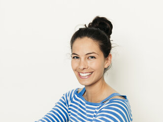 Beautiful young woman with black hair and blue white striped sweater is posing in front of white background - HMEF00426